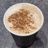 a cup of coffee with cinnamon sprinkles in it sitting on a countertop next to a cup of coffee.