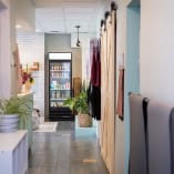 a long hallway with a bunch of towels hanging on the wall and a potted plant in the corner