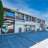 A building with a parking lot in front, trees nearby, displaying Invati Yoga & Wellness Okanagan signage.