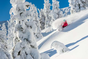 A person in red downhill skiing at Big White Ski Resort.