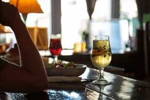 a person sitting at a bar with a plate of food and a glass of wine in front of them at Kettle River Brewing in Kelowna.