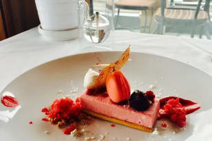 a white plate topped with a piece of cake next to a glass of water and a potted plant at Quails' Gate Winery in Kelowna