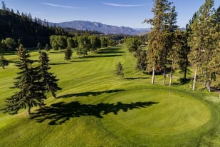 a view of a golf course with trees and a mountain in the background of the photo at Shannon Lake Golf Course, West Kelowna.
