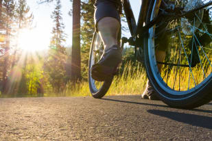 Close-up of a person riding a bike on a forest path during sunset.