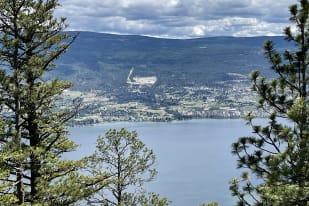A scenic view of Summerland with green hills, clouds in the sky, and a lake surrounded by trees.