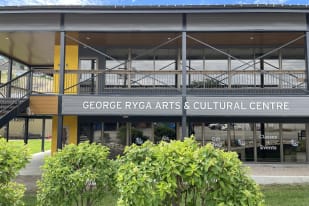The George Ryga Arts & Cultural Centre building with stairs and greenery in Summerland on a sunny day.
