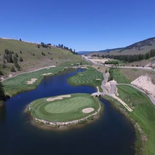 Aerial view of Black Mountain Golf Club in Kelowna, featuring a picturesque course with water hazards surrounded by hills and greenery under a clear blue sky
