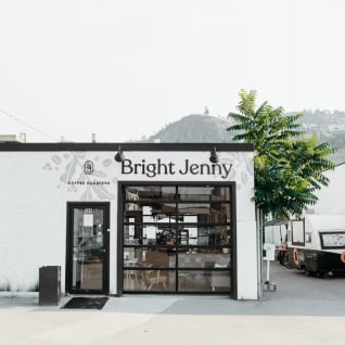 a white building with a sign that says bright jenny on the front of it and a tree in front of it