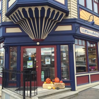 a store front with pumpkins and gourds in front of the front door of the store on a city street