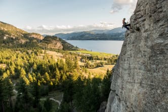 A rock climber rappels from the route Plumb Line on The Fortress with a view of Skaha Lake near Penticton