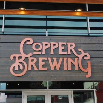 a sign that reads copper brewing above a door of a building with glass windows in Kelowna.