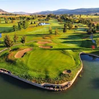 an aerial view of a golf course near a body of water with a bridge in the middle of it at Kelowna Springs Golf Club in Kelowna