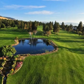 an aerial view of a golf course with a pond in the middle of the course and trees in the background at Sunset Ranch Golf & Country Club in Kelowna