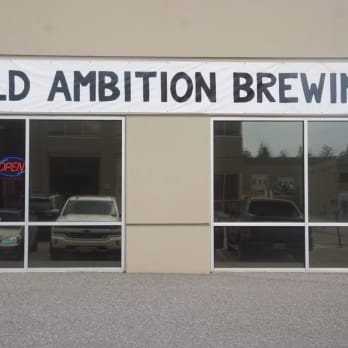 a building with a sign that says wild ambition brewing on the front of the building and a car parked in front of it