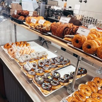 a display case filled with lots of different types of doughnuts on top of a wooden counter top