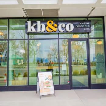 a storefront of kb&co restaurant in Kelowna with a signboard advertising their plant-based food options.
