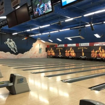 a bowling alley with multiple lanes and a mural featuring an astronaut and the Statue of Liberty on the wall at McCurdy Bowling Centre in Kelowna.