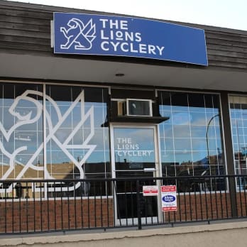 a building with a sign that says the lions cyclery on the front of it and a clock on the outside of the building