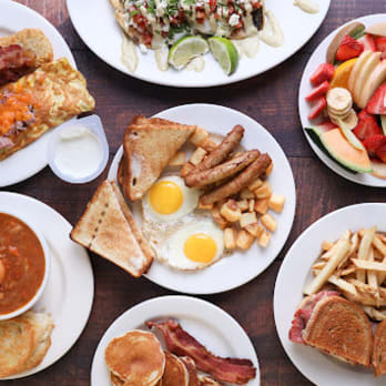 A variety of breakfast dishes including omelets, toast, fruit salad, eggs with sausage, soup, sandwiches, and fries from Bear's Den Restaurant in Penticton.