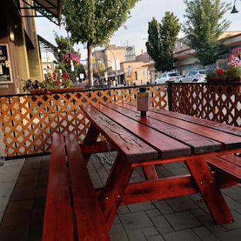 Outdoor seating area with a wooden picnic table and benches at The Hub on Martin, a bar & grill restaurant located in Penticton.