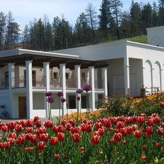 CedarCreek Estate Winery in Kelowna with a white building and vibrant red tulips in the foreground.