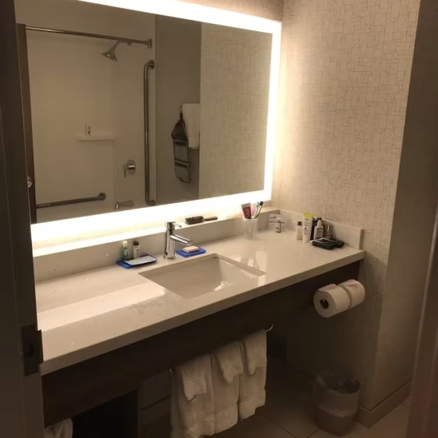 a bathroom with a sink, mirror and toilet paper rolls on the floor and a trash can in the corner of the room