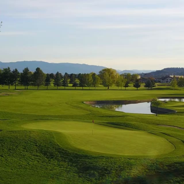 A view of a golf course with a pond in the foreground and a mountain in the background at Kelowna Springs Golf Club in Kelowna.