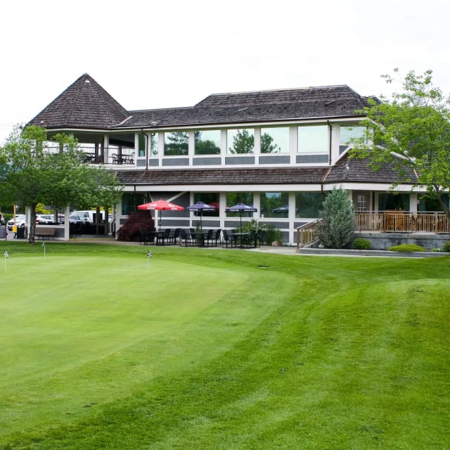 a golf course with a large building in the background and cars parked on the side of the road in front of it