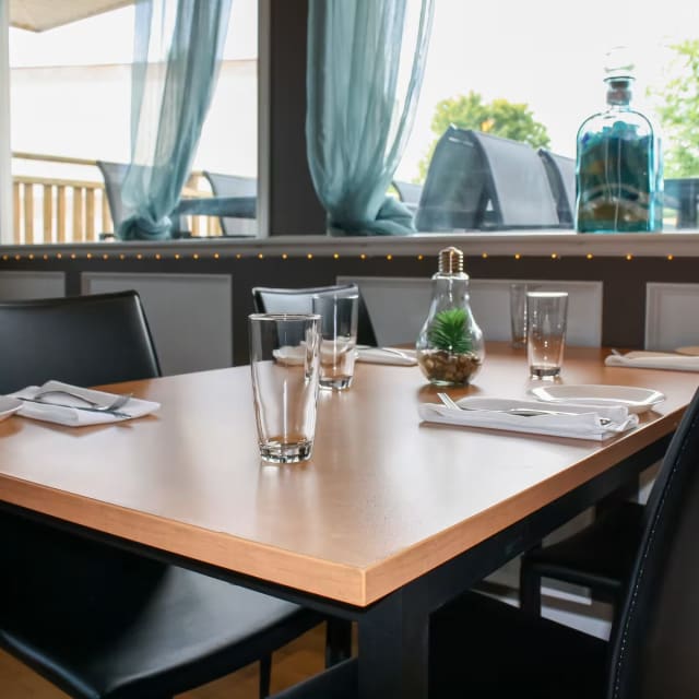 a wooden table with black chairs and a bottle of wine on top of a wooden table with plates and glasses on it at Mission Creek Golf Club in Kelowna