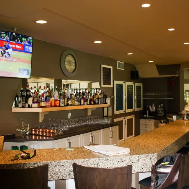a sports bar with a large screen tv and a bar with chairs and a table with drinks on it at Mission Creek Golf Club in Kelowna.