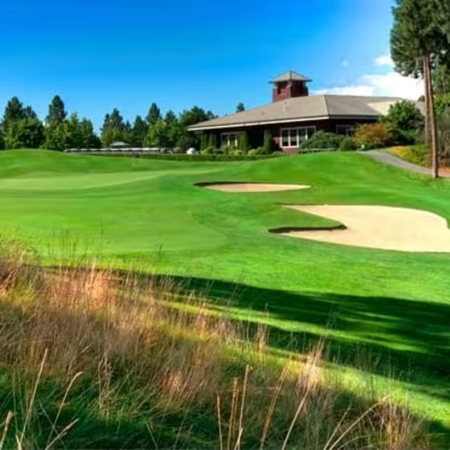 a view of a golf course with a house in the background and a golf green in the foreground