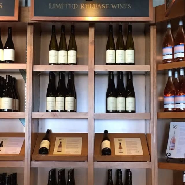 a shelf filled with bottles of wine on top of a wooden shelf next to a sign that says limited release wines