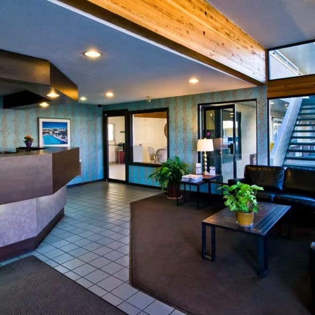 The lobby of a hotel with a large window and a staircase leading up to the second floor of the hotel.