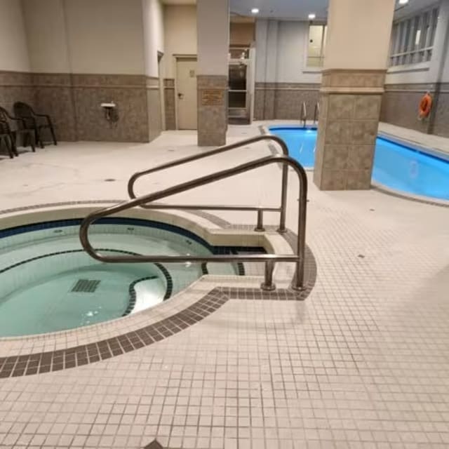 a large indoor swimming pool with stairs leading up to the pool and a hot tub in the middle of the room