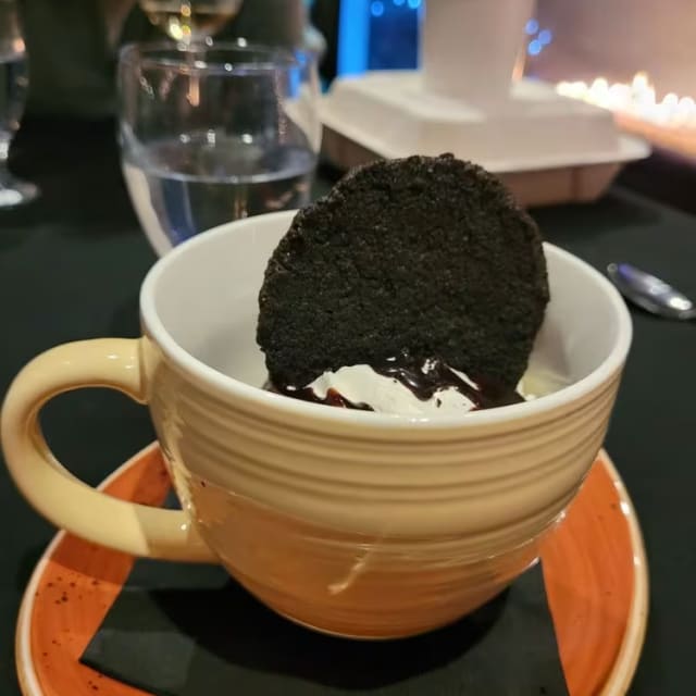 a cup of ice cream with a cookie in it on a saucer on a table next to a wine glass at The Club at Tower Ranch in Kelowna