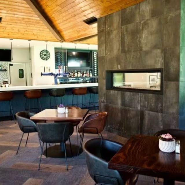 a restaurant with tables, chairs, and a bar in the back of the room with a clock on the wall