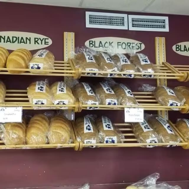 a display of breads and pastries for sale in a grocery store with price signs on the wall