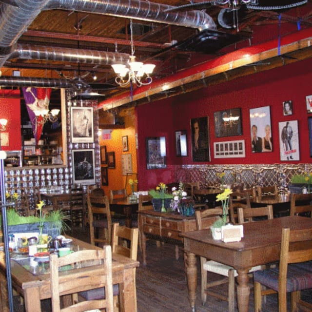 a restaurant with wooden tables and chairs and a chandelier hanging from the ceiling and pictures on the walls