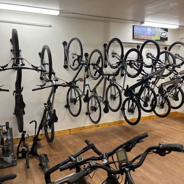 a room filled with lots of bikes and bicycles mounted to the wall next to a wall-mounted bike rack