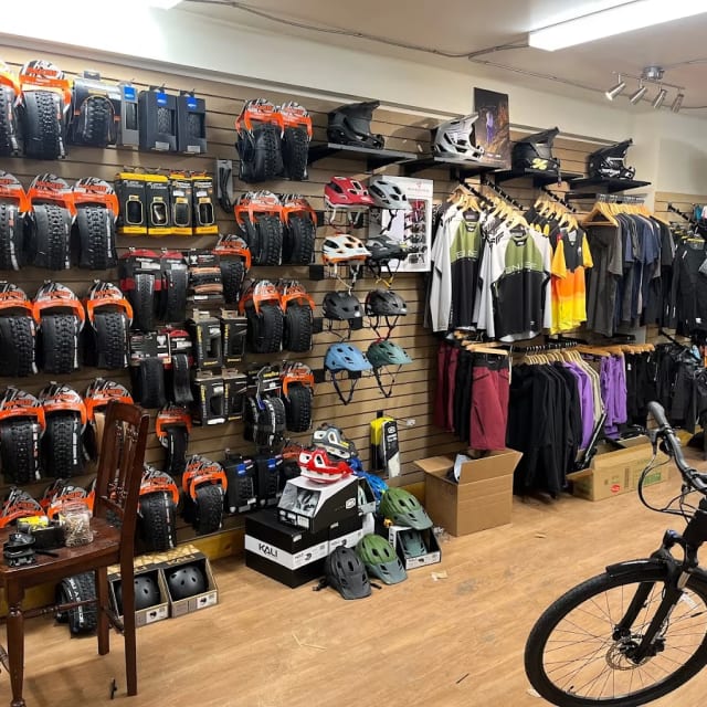 a store with a bicycle and a lot of items on the wall and a bike parked in front of it