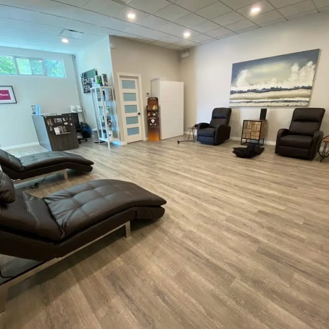 A spacious, modern spa room at The Recovery Spa in Kelowna with comfortable seating and contemporary decor.