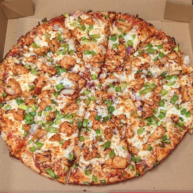 A delicious pizza with chicken, green peppers, onions, and melted cheese in an open cardboard box.