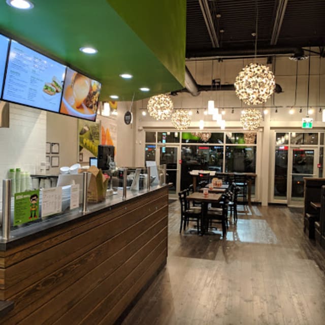 Interior of The Chopped Leaf health food restaurant with wooden countertops, modern lighting fixtures, and a seating area at the back.