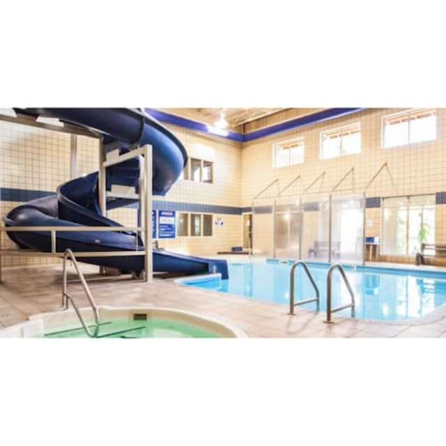 Indoor pool area at Coast Osoyoos Beach Hotel featuring a waterslide and hot tub under natural light.