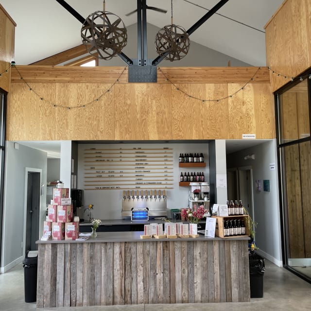 A modern rustic bar with a reclaimed wood counter, kegs, and bottles on shelves in Summerland.