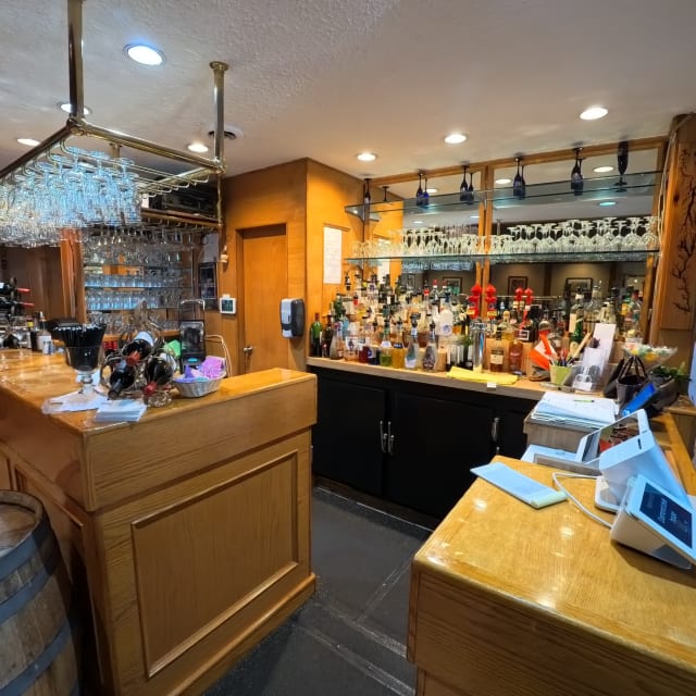 A well-lit wooden bar in Osoyoos, fully stocked with various bottles and glasses, ready for service.