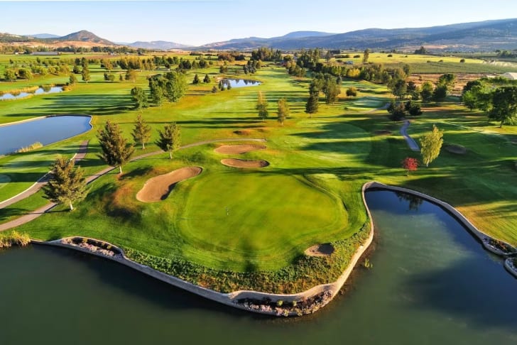 an aerial view of a golf course near a body of water with a bridge in the middle of it at Kelowna Springs Golf Club in Kelowna
