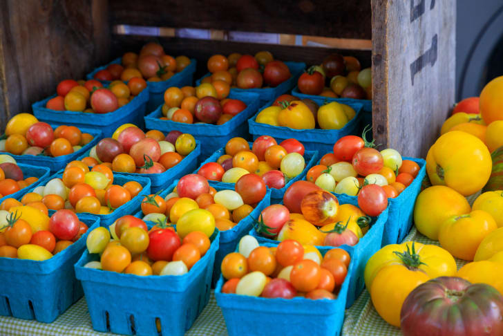 A market stall in Penticton displaying a variety of colorful tomatoes in blue containers.
