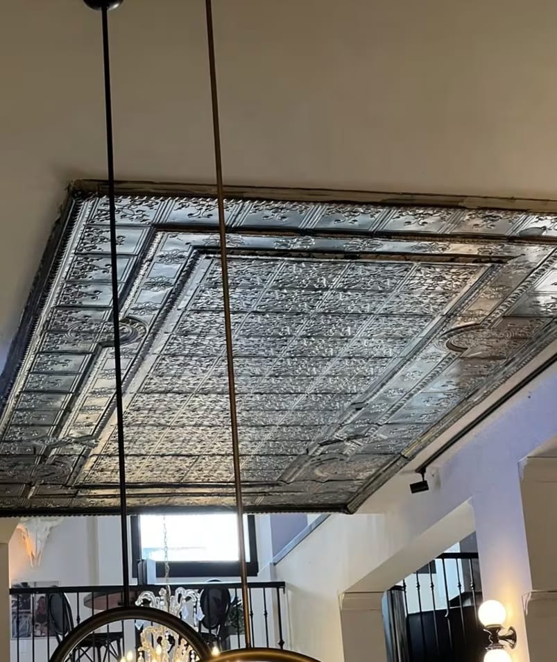 Ceiling view at Bernie's in Kelowna featuring ornate tiles and modern lighting fixtures.