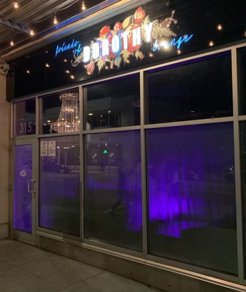 the front of a building with a lit up sign on the front of it and a purple light on the side of the building